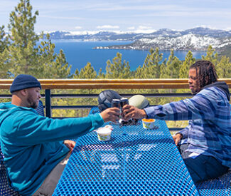 two men cheers at snowflake lodge overlooking lake tahoe