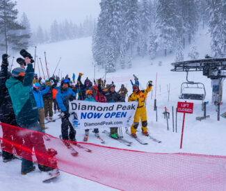 group of skiers in line holding now open sign